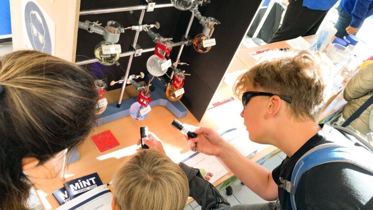 Schülerinnen und Schüler probieren sich an einem Experimentierstand aus