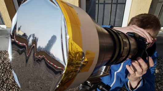 Ein Besucher beobachtet die partielle Sonnenfinsternis beim "Tag der Physik" an der Uni Jena.