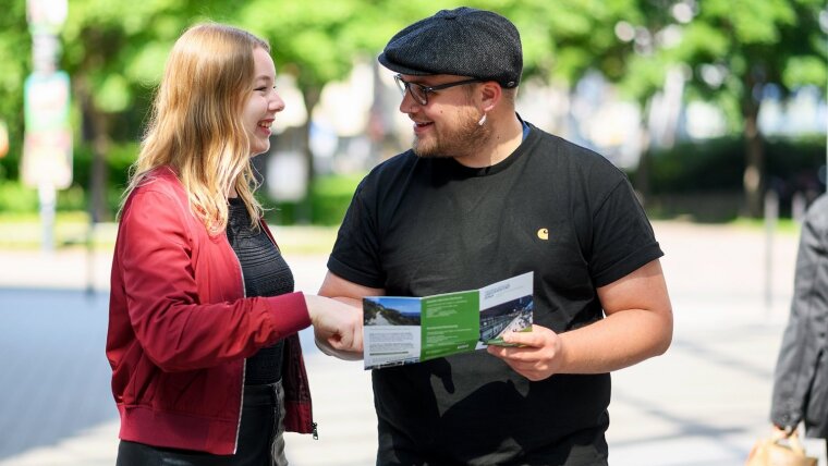 Zwei Studierende der Uni Jena mit einem Info-Flyer